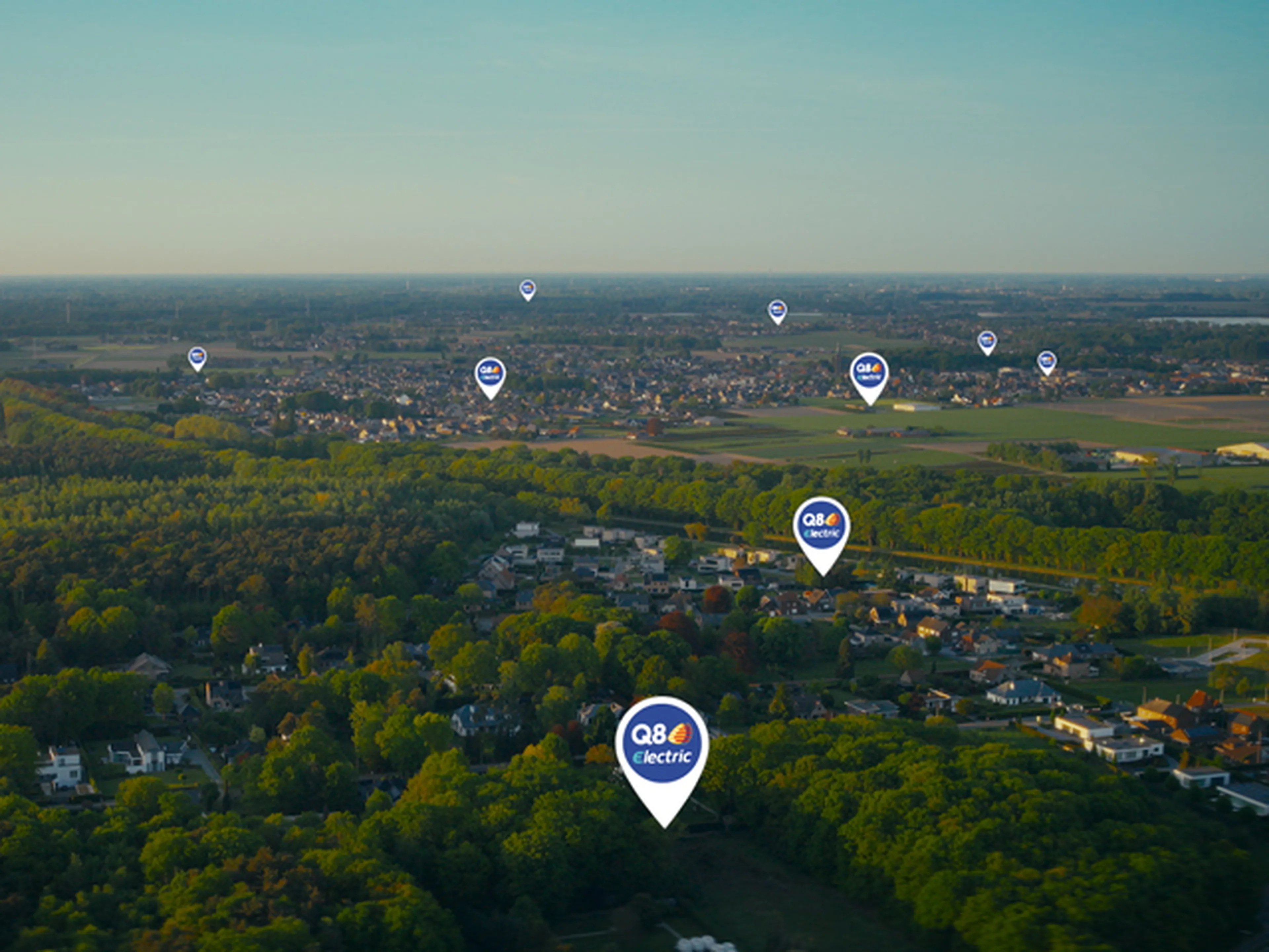 Luchtfoto van een landschap met meerdere locaties van Q8 electric-laadpunten gemarkeerd, als illustratie van een uitgebreid netwerk van laadstations.