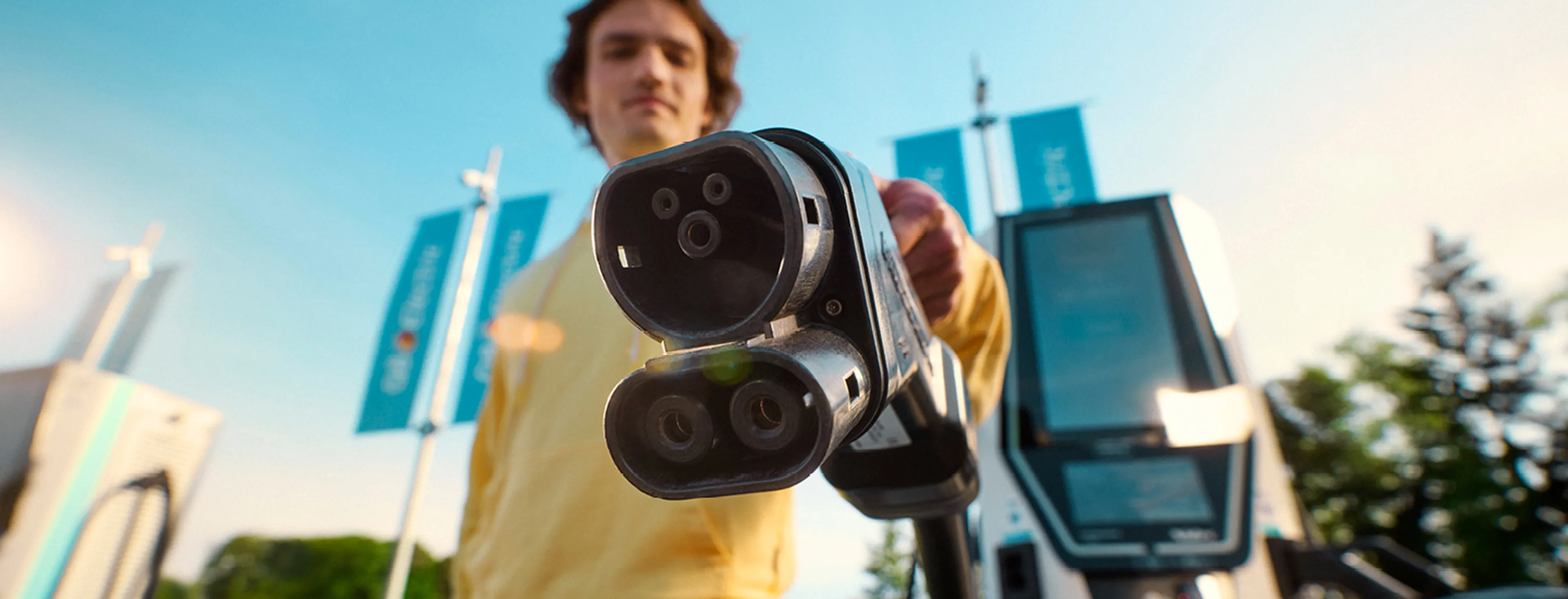 Person holding an electric vehicle charging connector in front of a Q8 electric fast charging station.